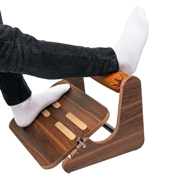 A wooden footrest with a dark brown wood grain finish and light tan accent strips, shown with a person's legs and feet resting on it against a plain white background.
